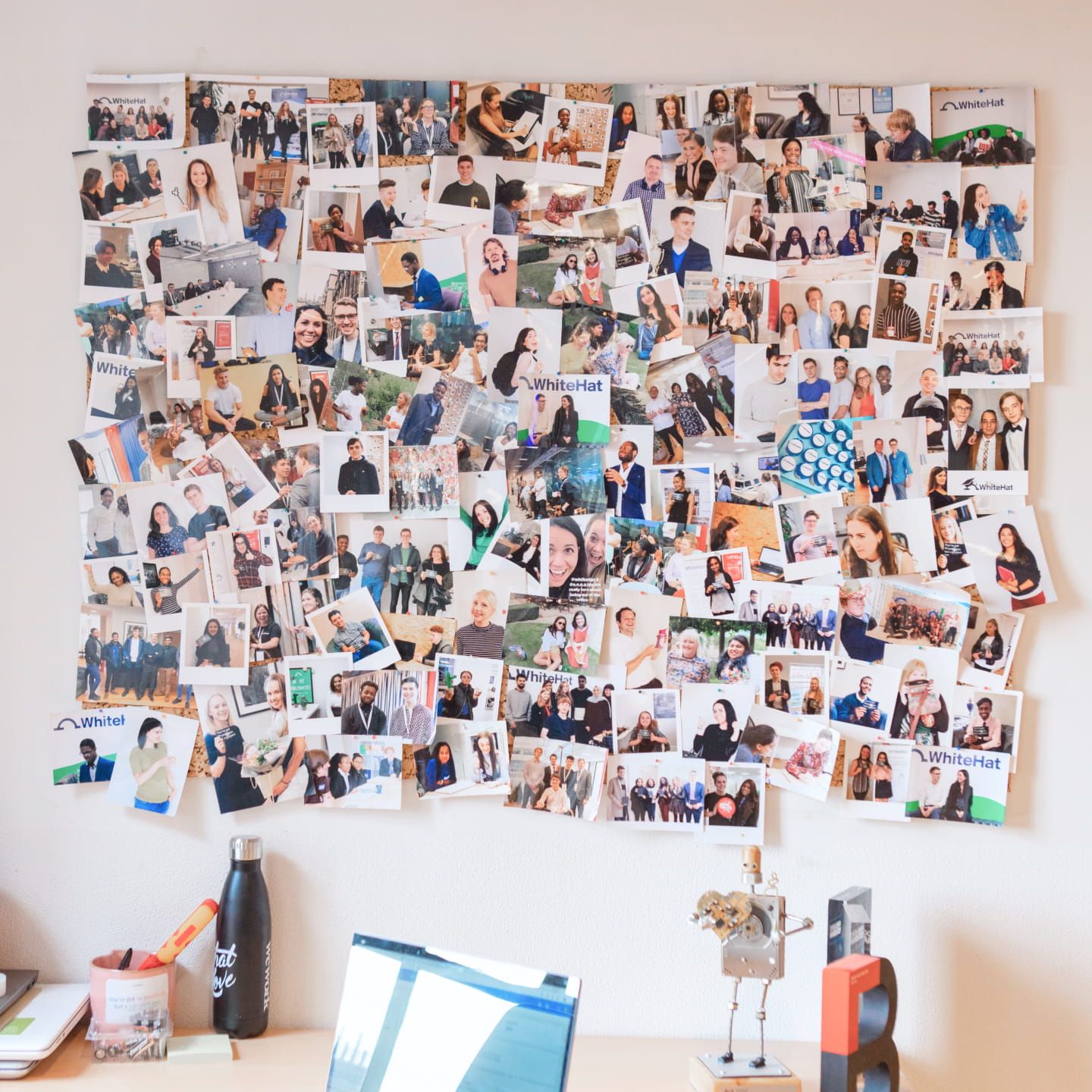A corkboard covered with dozens of different photos of smiling faces